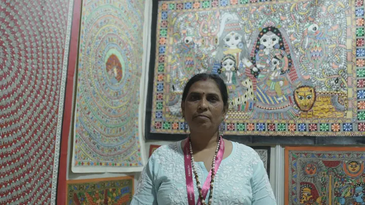 Artisan beside Madhubani paintings at FORHEX Fair 2025